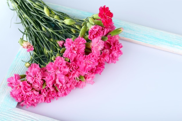 Mooi boeket van roze anjer met houten frame geïsoleerd op wit