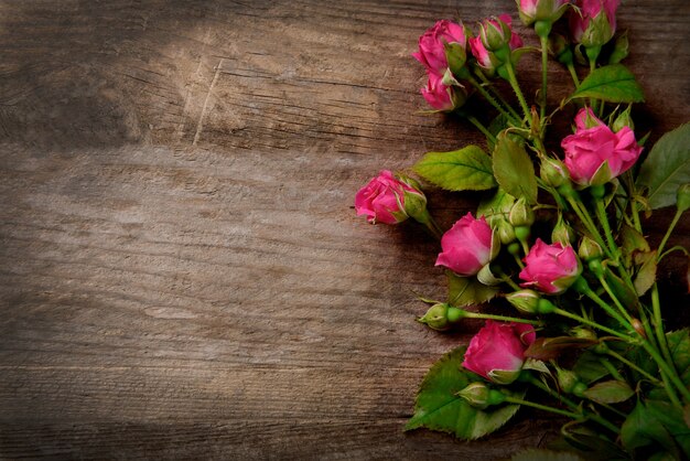 Mooi boeket van roze kleine rozen op houten, kopieer ruimte