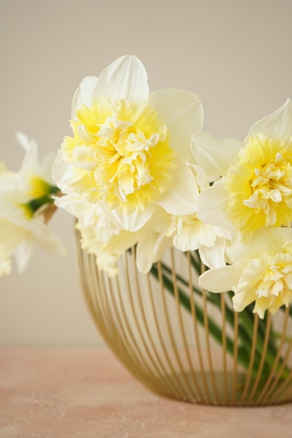 Mooi boeket van verse gele narcissen bloemen in vaas tegen beige achtergrond close-up lente bloeit verticaal