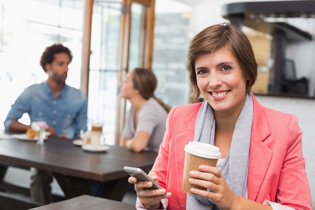 Mooi brunette die een tekst het drinken koffie verzenden