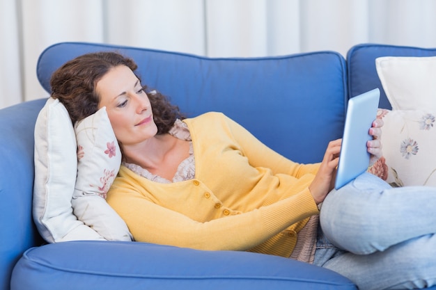 Mooi brunette die op de laag liggen en tablet gebruiken