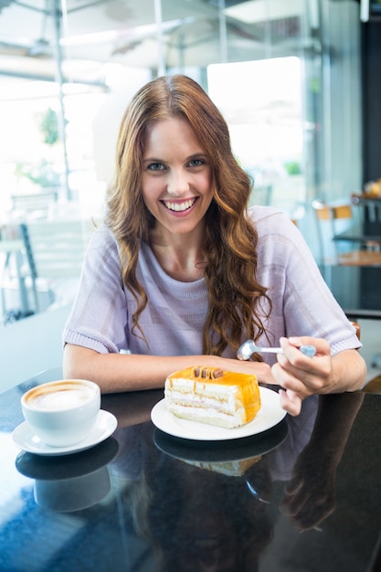 Mooi brunette die van een cake genieten