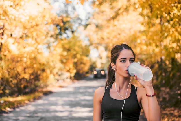 Mooi de vrouwen drinkwater van de geschiktheidsatleet na werkt het uitoefenen uit.