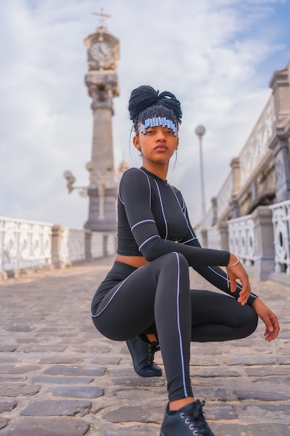 Mooi dominicaanse etnische meisje met met vlechten met volledig pak. fashion posé druzed naast een prachtige strandklok