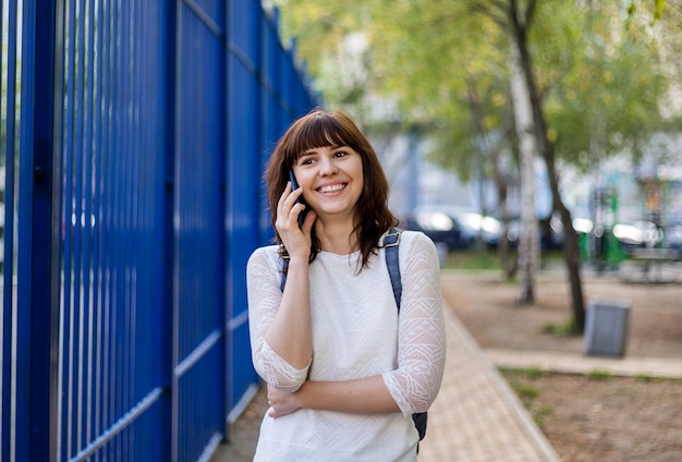 Mooi donkerbruin meisje die en op de telefoon op de straat glimlachen spreken. afstandsmededeling.