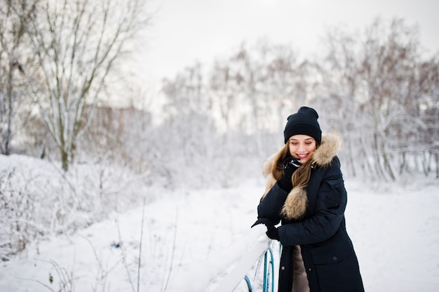 Mooi donkerbruin meisje in de winter warme kleding. Model op winterjas en zwarte hoed.