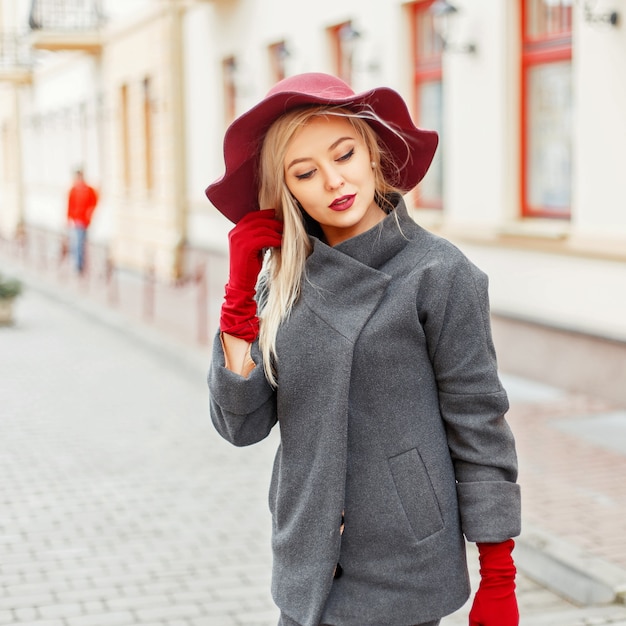 Mooi elegant meisje met mode hoed en grijze jas met een zwarte tas wandelen in de stad