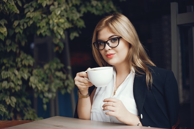 Mooi en stijlvol meisje, zittend in een cafe en drink een kopje koffie