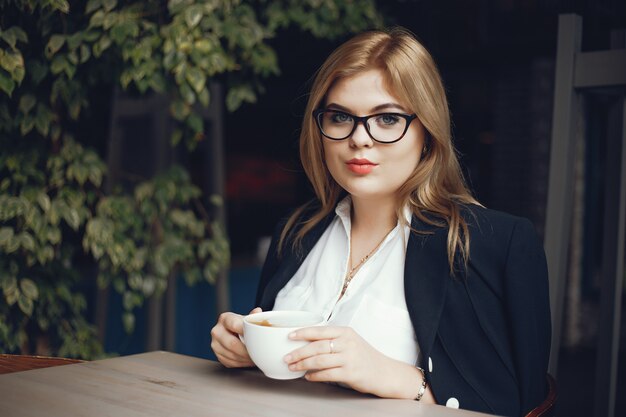 mooi en stijlvol meisje, zittend in een cafe en drink een kopje koffie