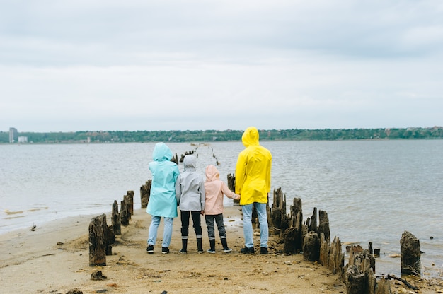 Mooi familieportret gekleed in kleurrijke regenjas dichtbij het meer