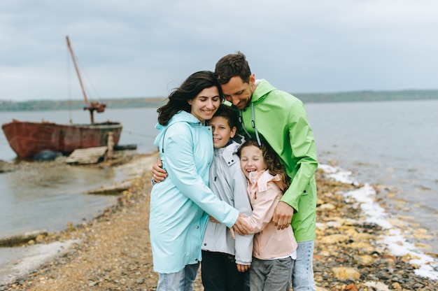 Mooi familieportret gekleed in kleurrijke regenjas dichtbij het meer