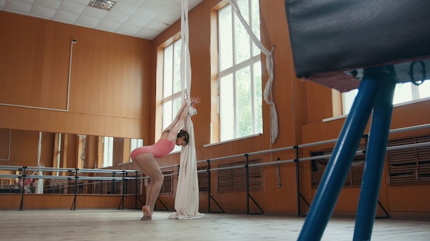 Foto mooi flexibel meisje aan het opwarmen in de balletbar, circusartiest