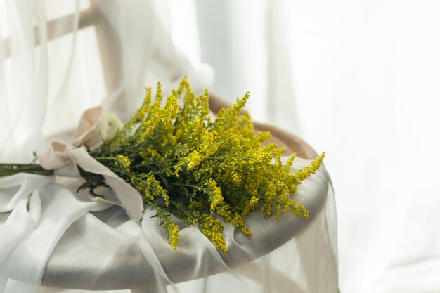 Mooi geel bloemboeket met witte linnendoek op houten stoel