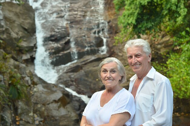 Mooi gelukkig bejaarde echtpaar rust in tropisch resort in de buurt van waterval