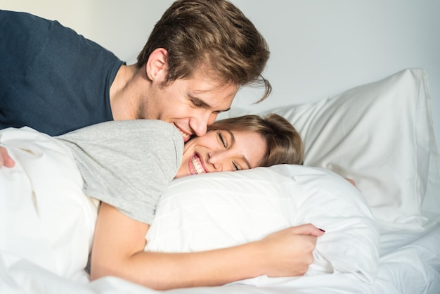 mooi gelukkig jong koppel knuffelen op bed