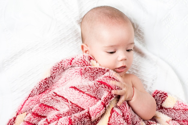 Mooi gelukkig klein babymeisje die in bed liggen