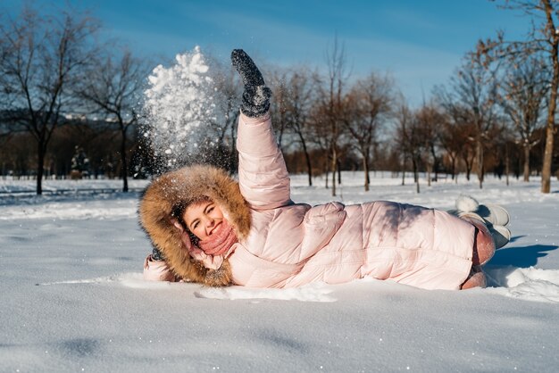 Mooi gelukkig lachend jong meisje met winter hoed, sjaal bedekt met sneeuwvlokken. Actieve levensstijl. Winter boslandschap achtergrond.