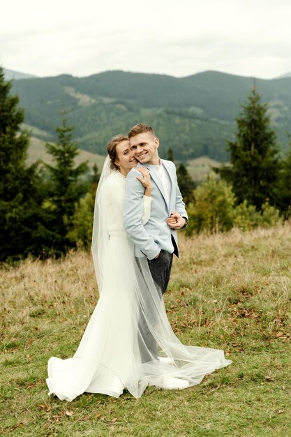 Mooi gelukkig lachend jong verliefd stel knuffelen in de bergen tegen de achtergrond van een prachtig landschapshuwelijksmoment