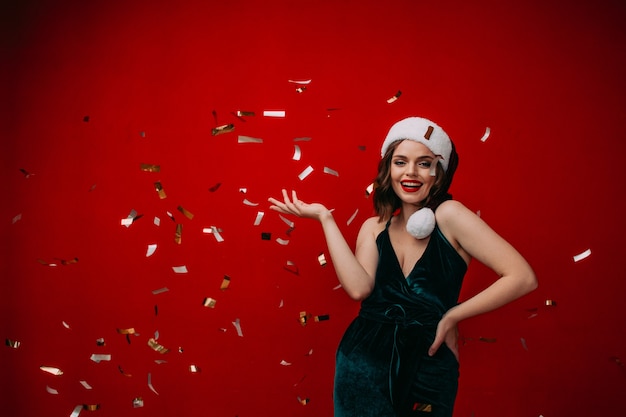 Mooi gelukkig meisje in een kerstmuts gooit confetti Nieuwjaar concept