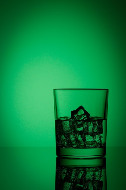 Mooi glas met ijs en water op een groene achtergrond