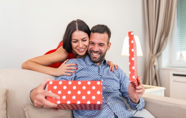 Mooi glimlachend jong koppel viert liefde voor verjaardag of verjaardag aantrekkelijke vrouw verrast hem met een geschenk