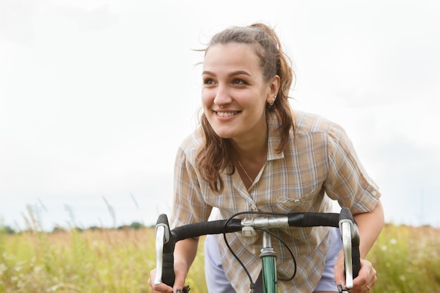 Mooi glimlachend jong vrouwenportret met fiets in een landweg