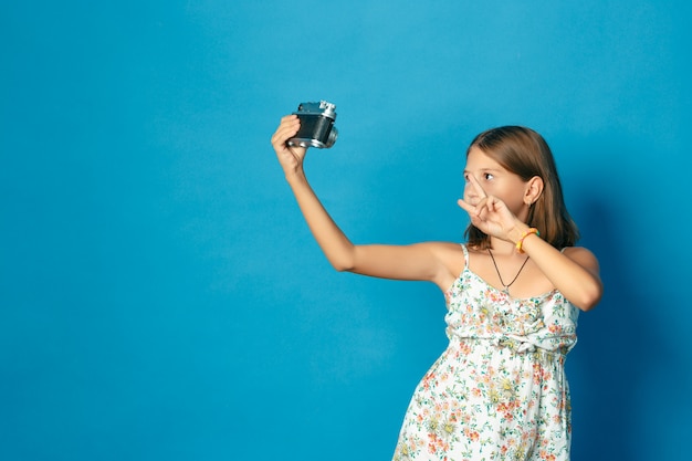 Mooi glimlachend kind (meisje) met witte tanden die een camera houden en selfie maken