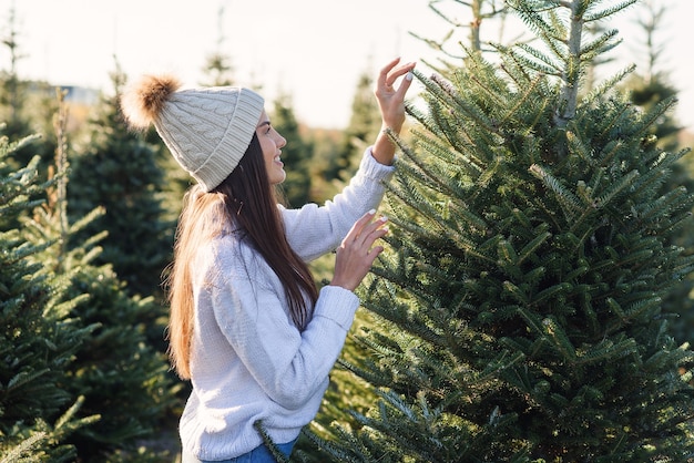 Mooi glimlachend meisje kiest een kerstboom op een plantage voor wintervakantie.