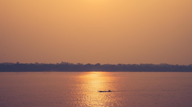 Mooi gouden zonlichtlandschap en silhouet met kleine vissersboot op de rivier