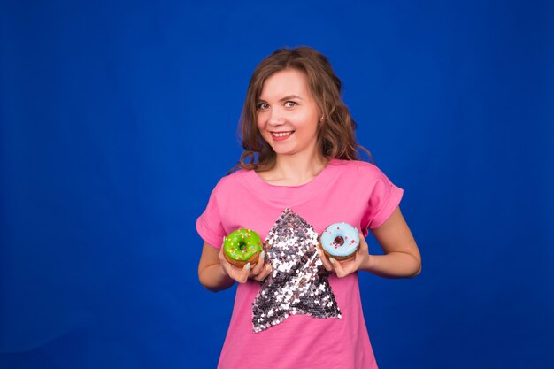 Mooi grappig meisje met donuts op blauw.