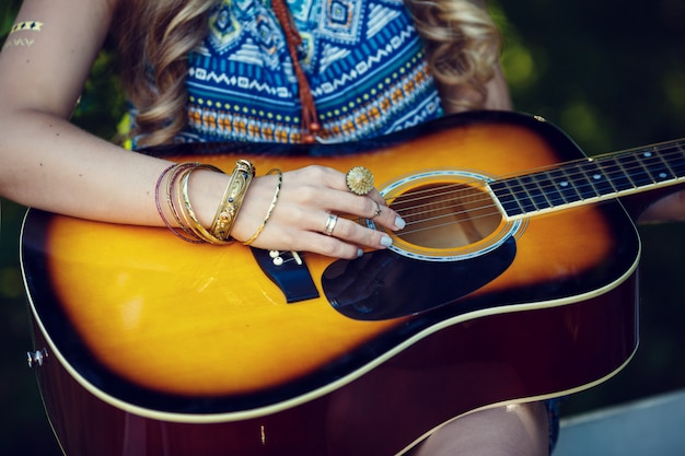 Mooi hippiemeisje met gitaar in park bij zonsondergang