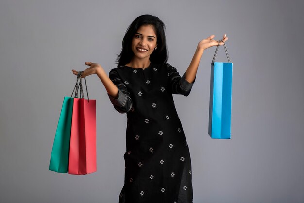 Mooi Indisch jong meisje houden en poseren met boodschappentassen op grijs