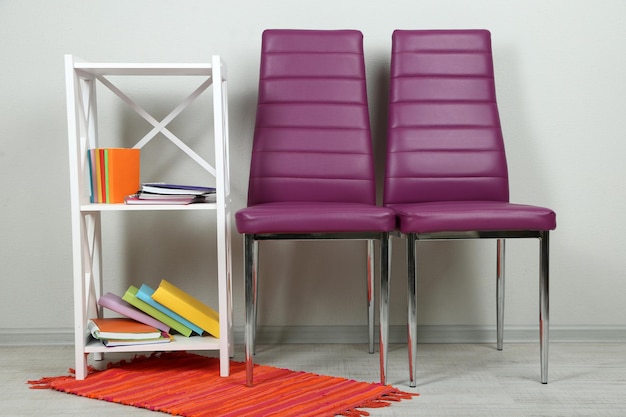 Mooi interieur met moderne kleur stoelen boeken op houten standaard op muur achtergrond