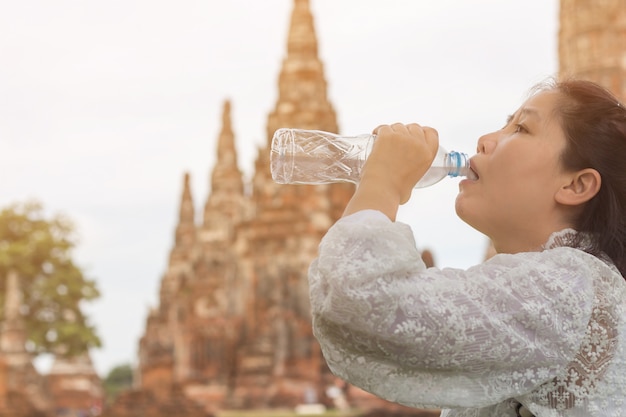 Mooi jong Aziatisch vrouwen drinkwater na rustende gang in vakantie bij Wat Chai Watthanaram-tempel, fles van de reizigers de vrouwelijke holding zuiver water