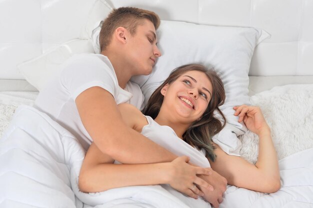 Mooi jong echtpaar op een zacht bed in de ochtend.