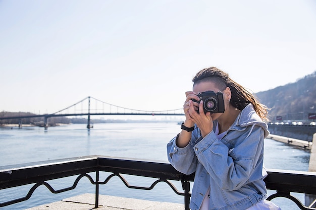 Mooi jong Kaukasisch meisje met dreadlocks die een retro camera in haar handen houden - fotografie als hobby in het reizen