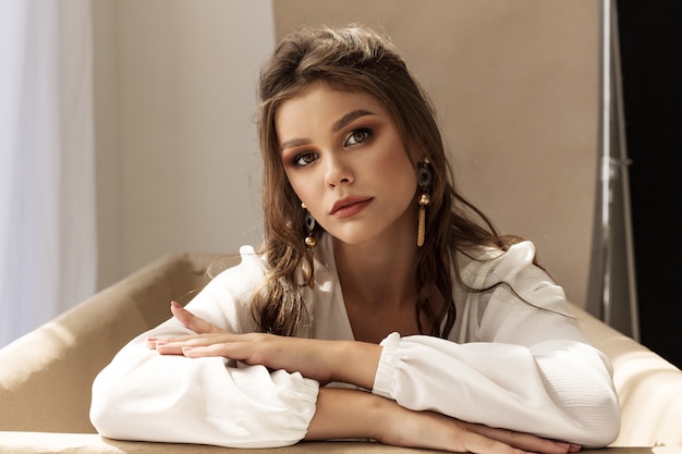 Mooi jong krullend donkerbruin meisje in witte blouse en grijze broek