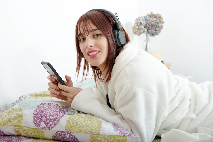 Mooi jong meisje dat aan muziek in haar bed luistert