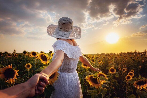 Mooi jong meisje genieten van de natuur op het gebied van zonnebloemen bij zonsondergang