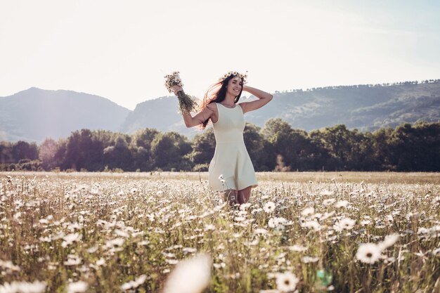 Mooi jong meisje glimlachend over kamille veld Zorgeloze, gelukkige brunette vrouw met gezond lang haar die plezier heeft buiten in de natuur