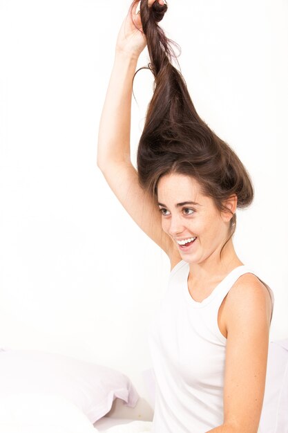 Mooi jong meisje in bed dat haar zeer lang bruin haar toont