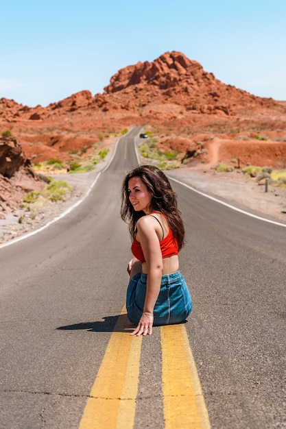 Mooi jong meisje in een spijkerrok op een schilderachtige weg in Valley of Fire Nevada