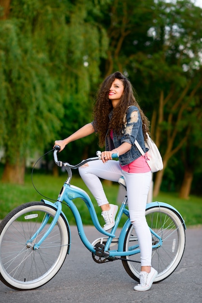 Mooi jong meisje in vrijetijdskleding rijdt in de zomer op een stadsfiets