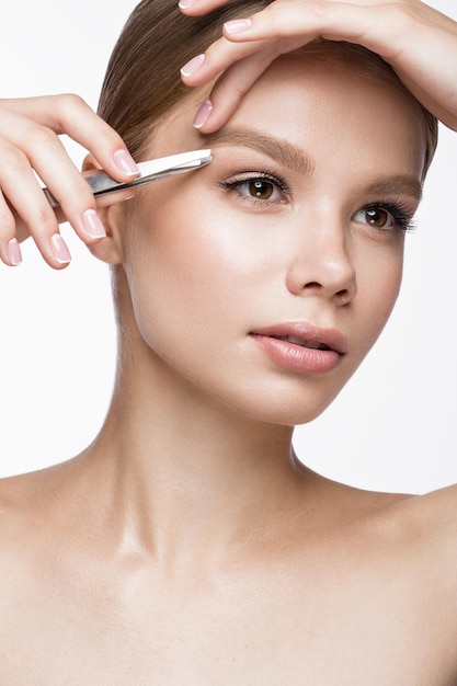 Mooi jong meisje met een lichte natuurlijke make-up, wenkbrauwpincet en French manicure. Mooi gezicht. Foto genomen in de studio op een witte achtergrond.