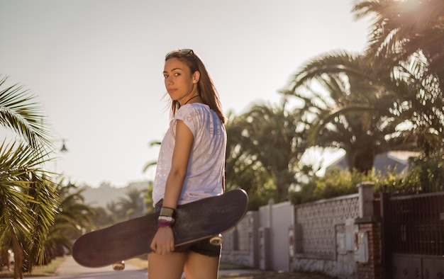 Mooi jong meisje met een skateboard buiten op de zomer