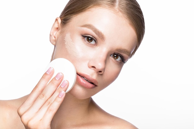 Mooi jong meisje met spons voor applicatie make-up en French manicure. Mooi gezicht. Foto genomen in de studio op een witte achtergrond.