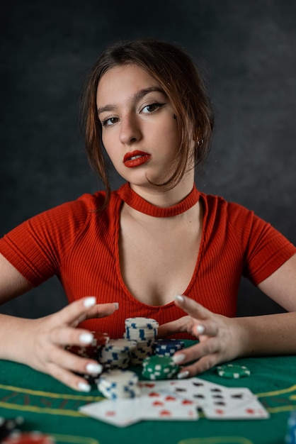 Mooi jong meisje zit aan een poker tafel met kaarten in haar handen poker spel van toeval handen van de vrouw houden poker kaarten