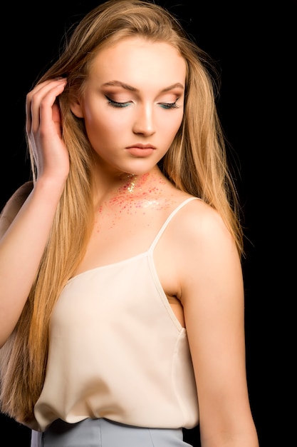 Mooi jong model met glitter op haar nek in donkere studio