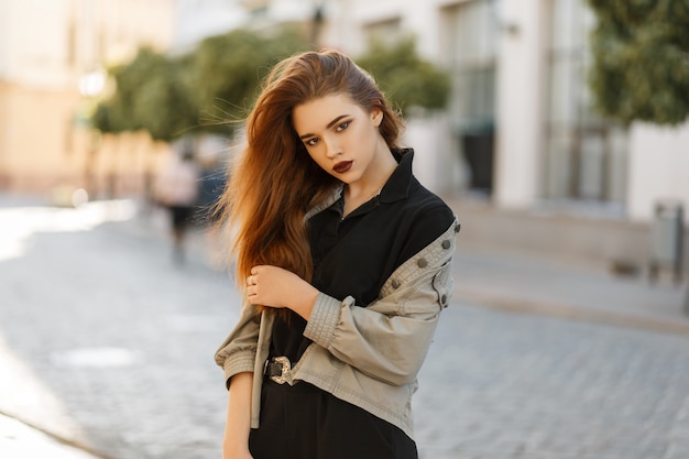 Mooi jong modelmeisje in modieus jasje en zwart poloshirt poseren in de stad