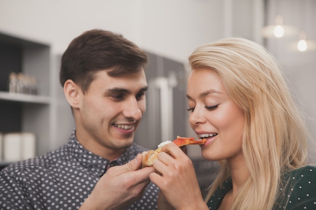 Mooi jong paar dat pizza samen eet bij de keuken